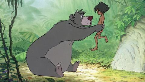 In einem Bild aus dem Disney-Trickfilm "Das Dschungelbuch" hält der Bär Balu Mogli in die Höhe.