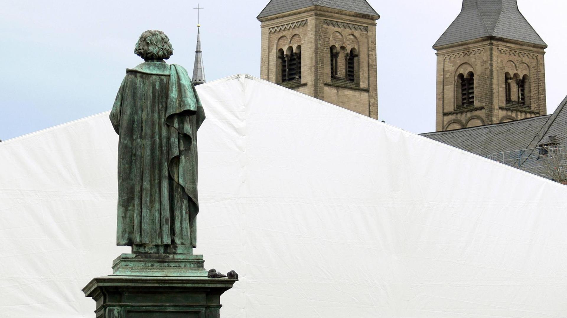 Die Bonner Statue Beethovens in Rückenansicht, die scheinbar auf die Türme des Bonner Münsters schaut.