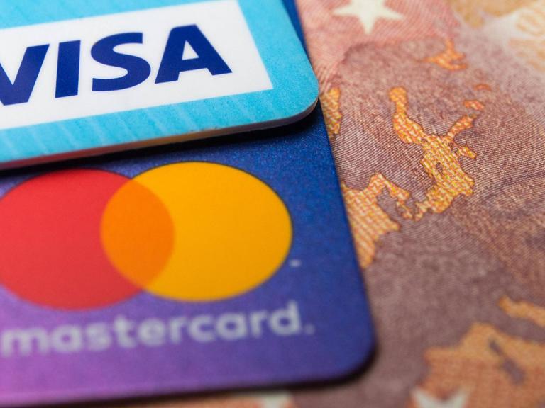 Eine Visa- und eine Mastercard-Kreditkarte auf einem 50-Euro-Schein