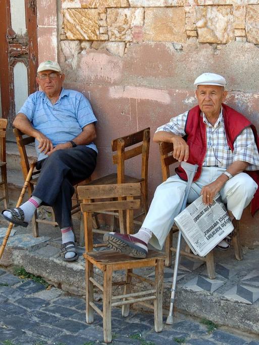 Türkische Rentner sitzen vor einem Haus in Ayvalik.