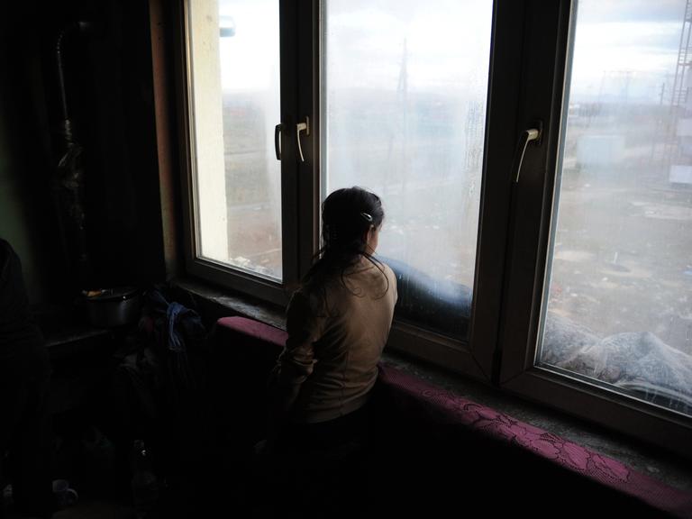 Eine Mädchen schaut Plementina bei Pristina im Kosovo aus dem Fenster einer Wohnung fotografiert am