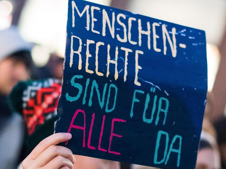 Bei einer Demonstration in Frankfurt hält eine Frau ein Schild mit der Aufschrift "Menschenrechte sind für alle da".