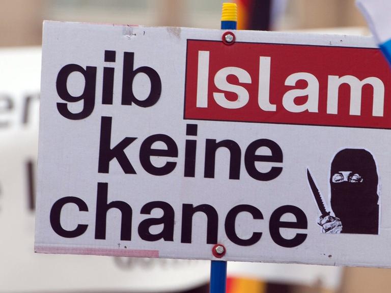 Ein Anhänger des islamkritischen Pegida-Bündnisses hält während einer Kundgebung ein Schild mit der Aufschrift "gib Islam keine chance".