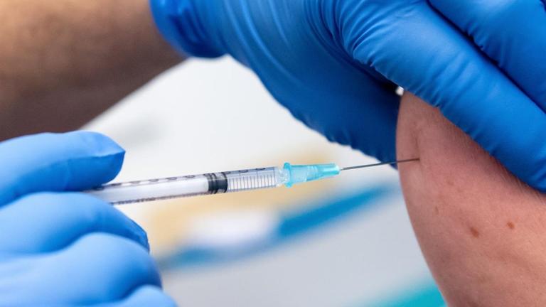 Nahaufnahme: Einem Patienten wird ein Impfstoff gespritzt.