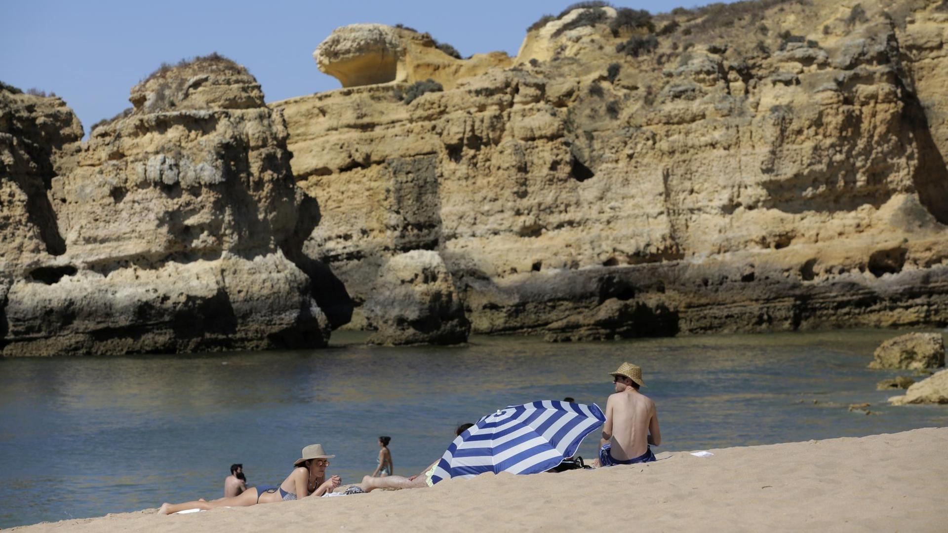 Menschen sitzen an einem Strand in dem Land Portugal.