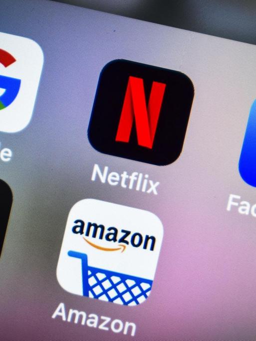 Auf dem Display eines Smartphones sind die Logos von Apple, Amazon, Netflix, Facebook und Google zu sehen.