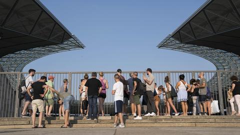 Besucher stehen vor der Umzäunung des Berliner Olympiastadions und blicken hinein.