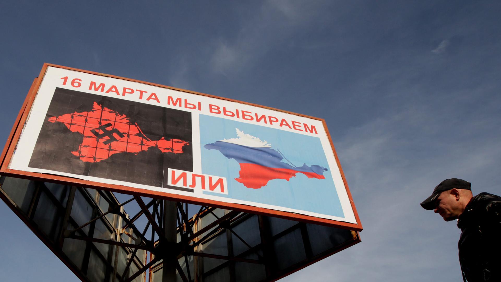 Plakate in Sevastopol rufen zur Teilnahme am Referendum auf. Ein Mann geht darunter vorbei.
