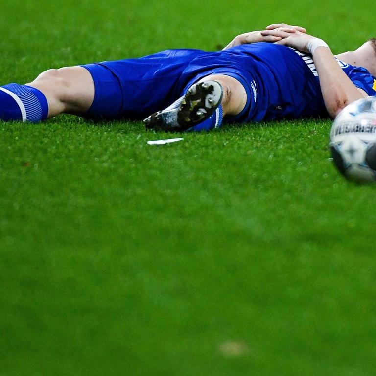 Ein Spieler im blauen Trikot liegt auf dem Rasen, neben ihm ein Fußball.