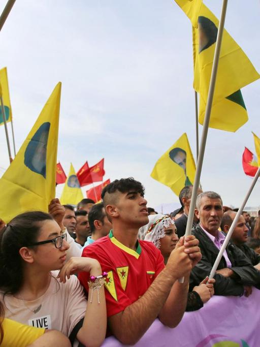 Kurden schwenken gelbe Fahnen mit Öcalan-Porträt