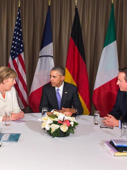 Renzi, Merkel, Obama, Cameron und Fabius sitzen an einem Tisch und reden, hinter ihnen die Flaggen ihrer Länder.