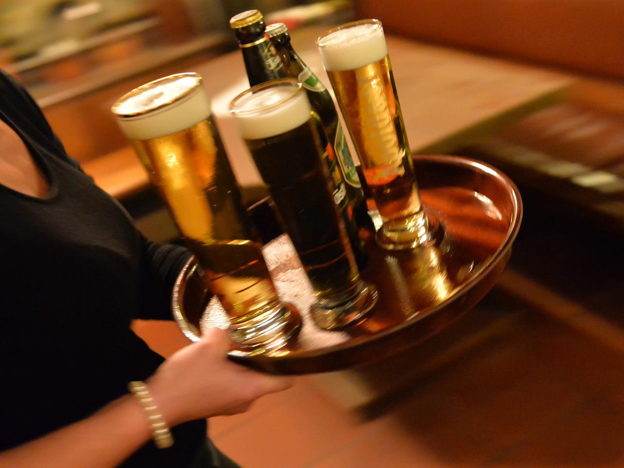 Eine Bedienung trägt am 29.10.2013 in Erfurt (Thüringen) in einem Lokal ein Tablett mit Bier.