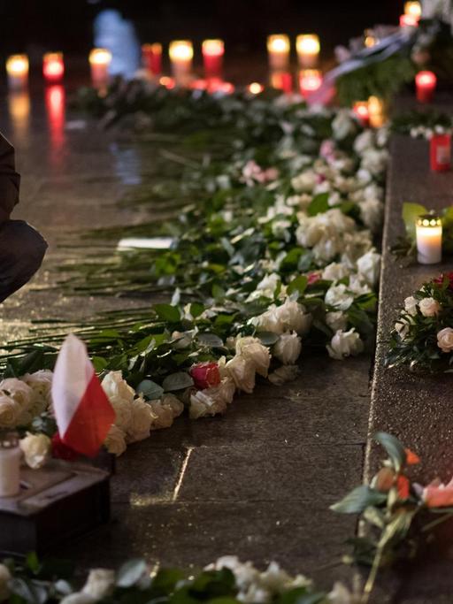 Eine Frau stellt am 19.12.2017 an der Gedenkstätte für die Opfer des islamistischen Terroranschlags auf dem Weihnachtsmarkt an der Gedächtniskirche auf dem Breitscheidplatz in Berlin eine Kerze auf. Bei dem Anschlag vor einem Jahr war der Attentäter Anis Amri mit einem gestohlenen Lastwagen in den Weihnachtsmarkt am Breitscheidplatz gefahren. Zwölf Menschen wurden getötet, fast 100 verletzt.