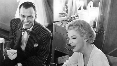 Der Schauspieler Frank Sinatra lacht mit der Schauspielerin Viviane Blaine bei den Dreharbeiten zu "Schwere Jungs - leichte Mädchen" (Guys and dolls) im Jahr 1956.