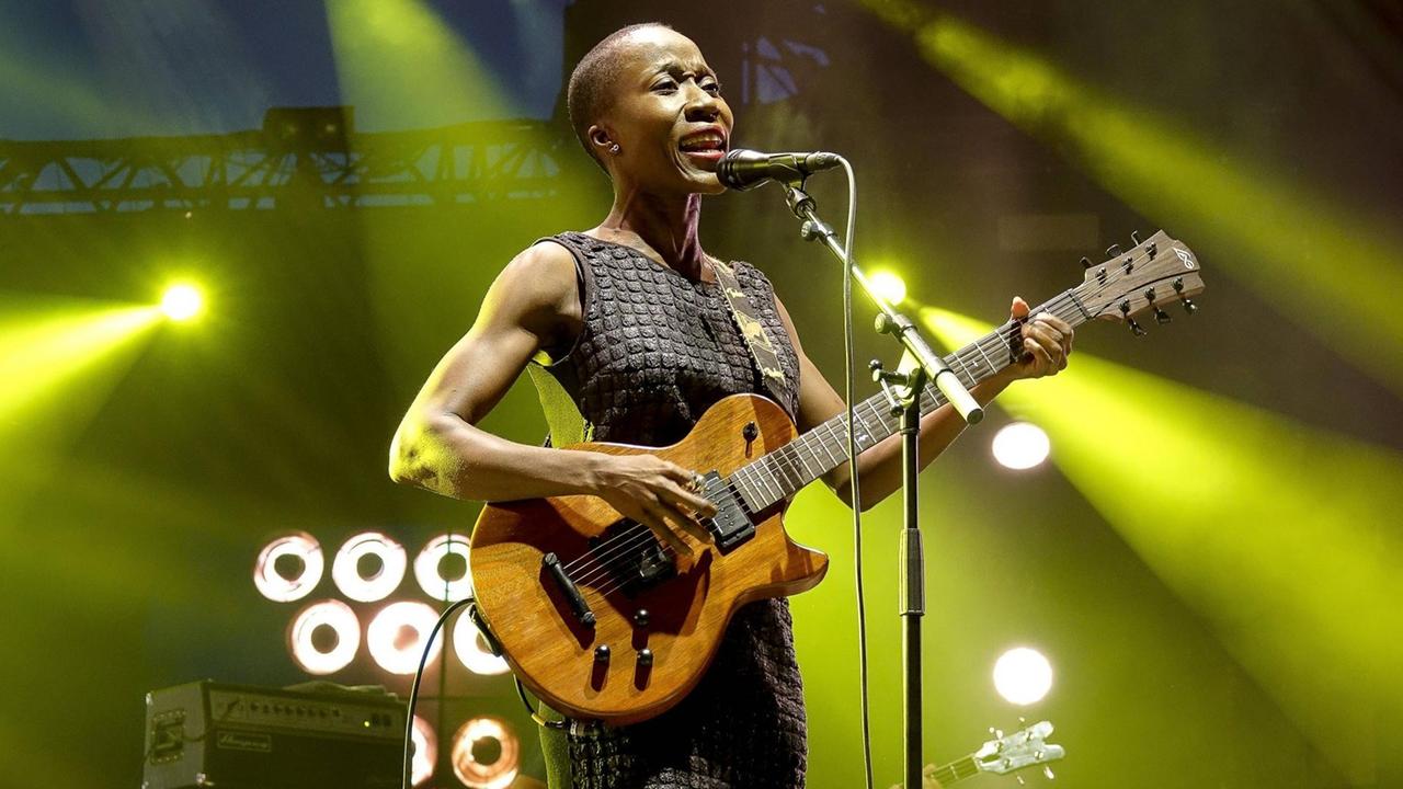 Rokia Traoré steht auf einer Bühne und spielt Gitarre.
