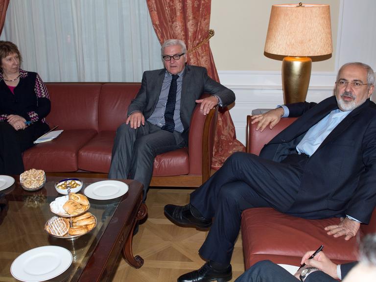 Die ehemalige EU-Außenbeauftragte Catherine Ashton mit Bundesaußenminister Frank-Walter Steinmeier und Irans Außenminister Mohammad Javad Zarif sitzen auf roten Sofas.