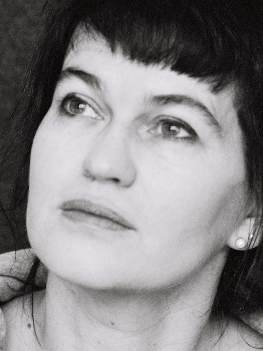 Eine schwarz-weiße Porträtaufnahme der Autorin Karin Kalisa. Sie blickt Richtung linker oberer Bildecke.