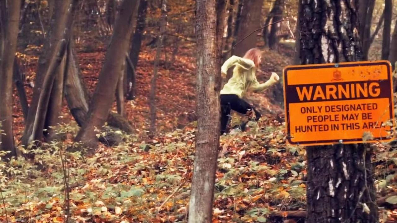 Eine Frau läuft durch einen Wald - Filmausschnitt aus "The Hunt".