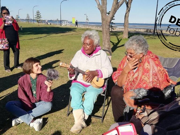 Die Autorin und zwei Damen spielen Ukulelenlieder beim Picknick der Unserdeutsch Community in Brisbane.