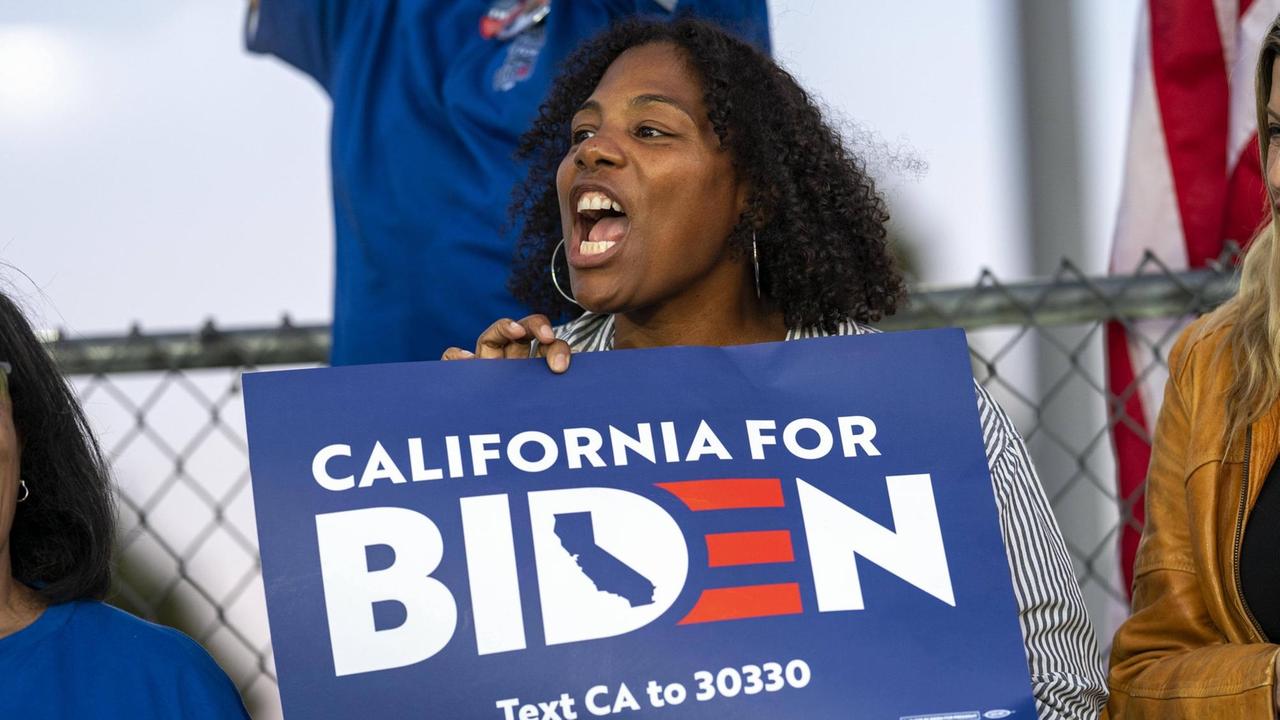 Eine afroamerikanische Frau hält ein Schild mit der Aufschrift "California for Biden" in ihren Händen.