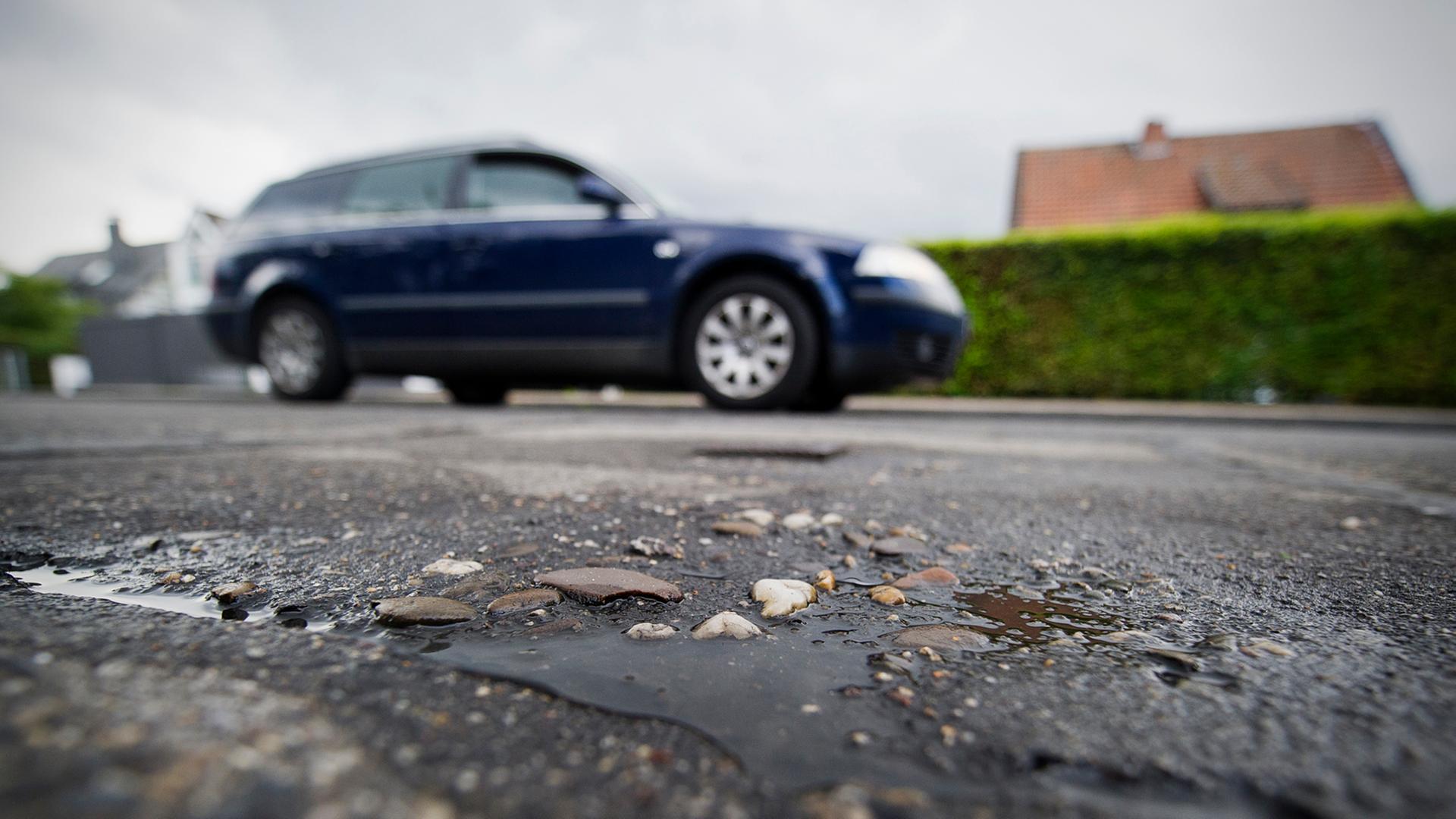 Ein Auto fährt am 19.08.2013 an einem geflicktem Schlagloch in einer Straße in Büderich (Nordrhein-Westfalen) vorbei.