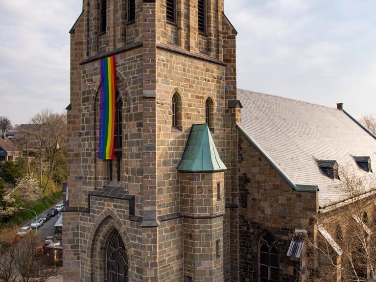 Eine Regenbogenfahne hängt an einem Kirchturm