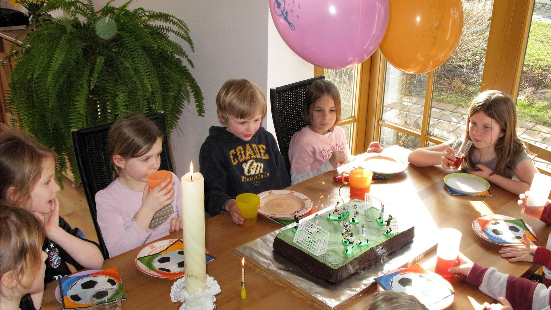 tellerKinder feiern einen Kindergeburtstag an einem bunt gedeckten Tisch.