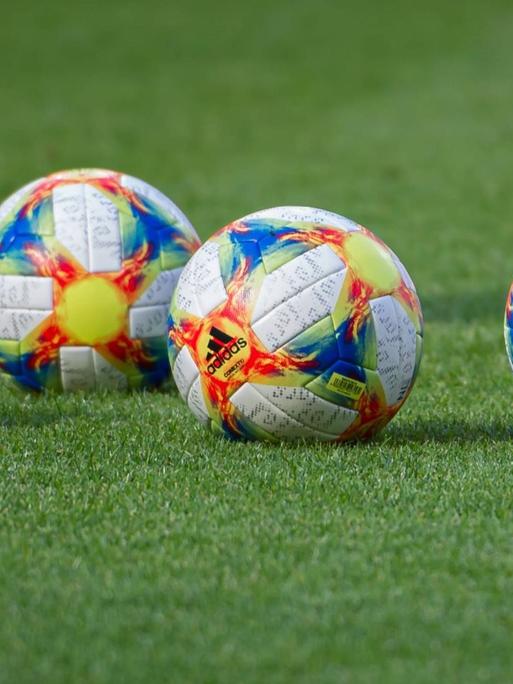 Fünf offizielle Spielbälle der Fußball-WM der Frauen 2019 liegen auf dem grünen Rasen.