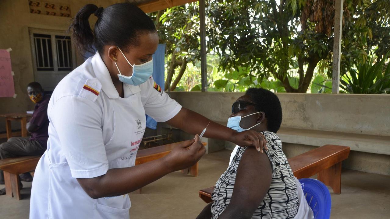 Eine medizinische Mitarbeiterin hält eine Spritze in der Hand und impft eine Frau gegen Covid-19.