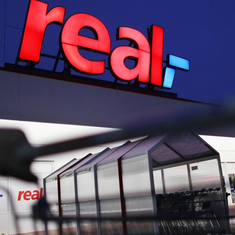 Ein Mann schiebt seinen Einkaufswagen vor einem Real Supermarkt. Ein Mann schiebt seinen Einkaufswagen vor einem Real Supermarkt.