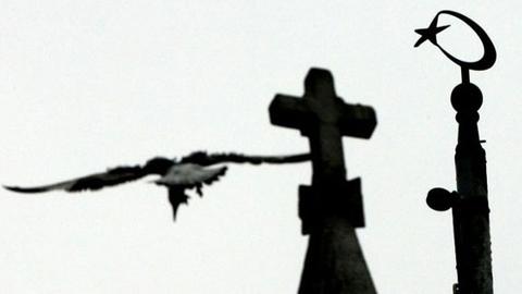 Ein Halbmond mit Stern neben dem Kreuz auf einem Kirchturm