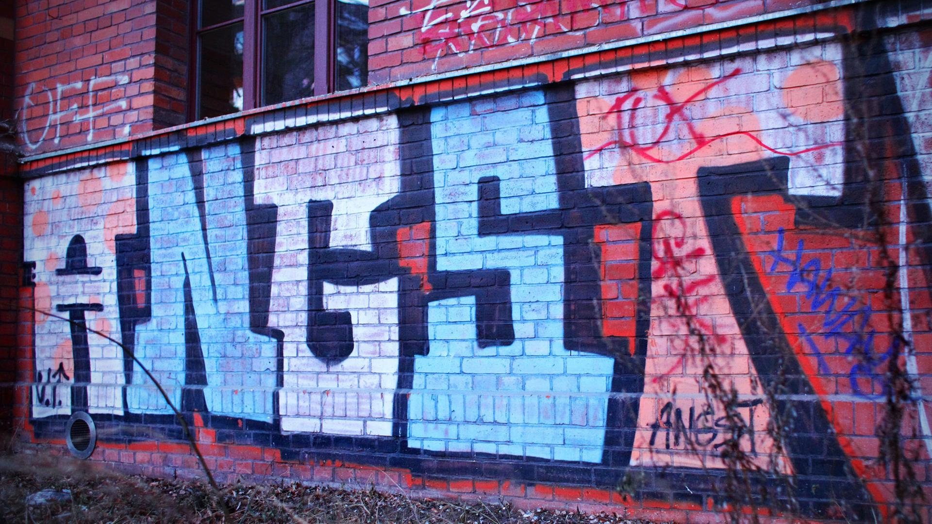 Ein Graffiti mit dem Wort "Angst" auf einer Backsteinwand eines Hauses