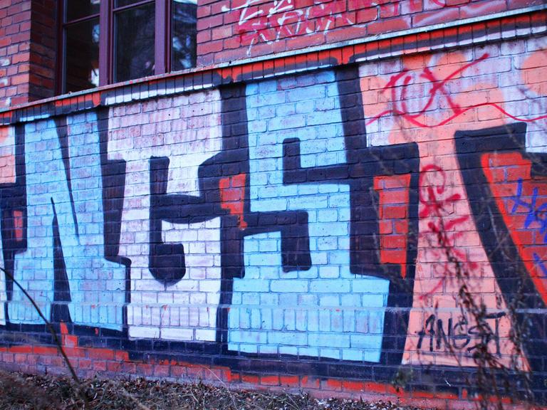 Ein Graffiti mit dem Wort "Angst" auf einer Backsteinwand eines Hauses