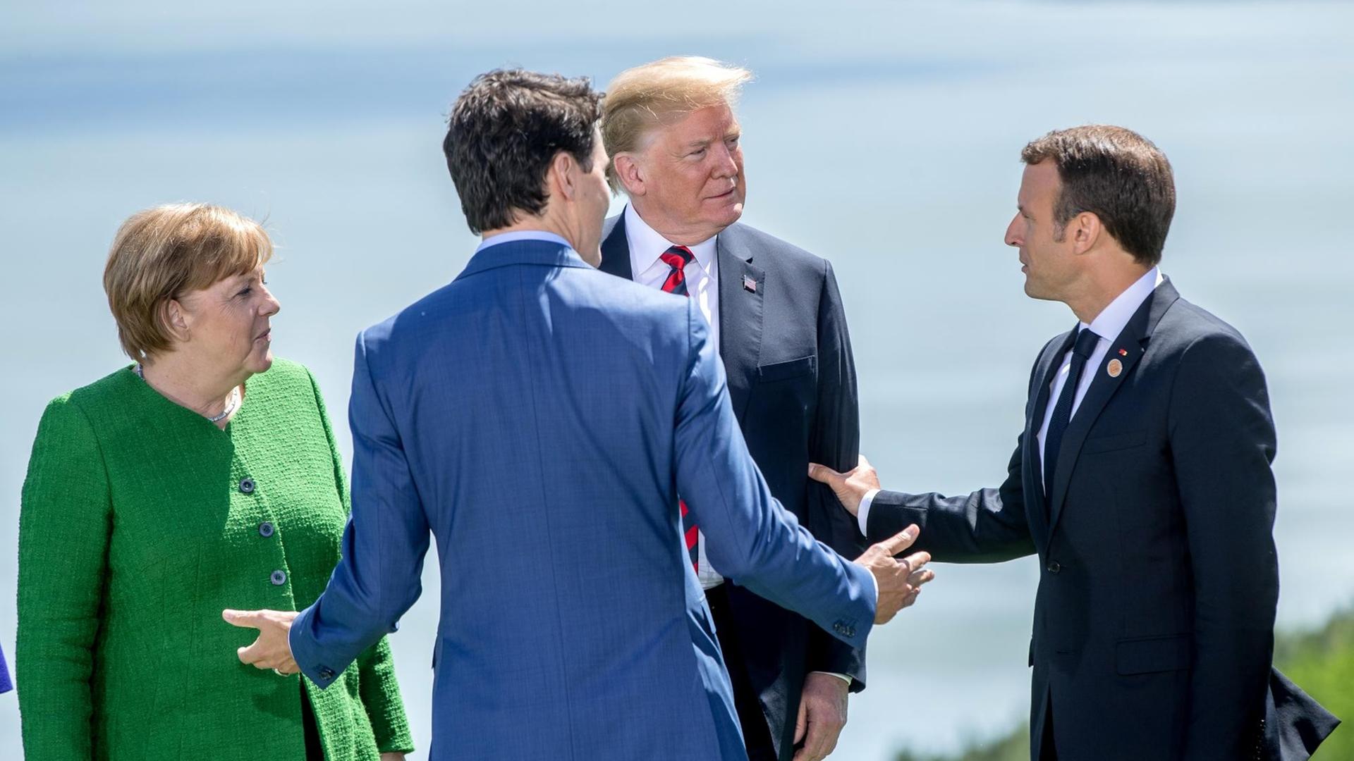 Bundeskanzlerin Angela Merkel (CDU,l), spricht mit Donald Trump, Präsident der USA (M), Emmanuel Macron, Präsident von Frankreich (r) und Justin Trudeau, Premierminister von Kanada. Das Gipfeltreffen der G7 findet in Charlevoix unweit der Ortschaft La Malbaie in der Provinz Québec statt.