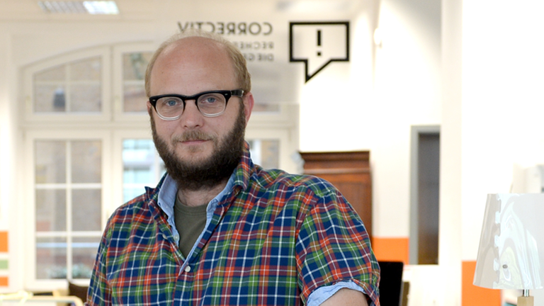 David Schraven mit Bart und Brille im Büro des Recherchekollektivs "Correctiv".