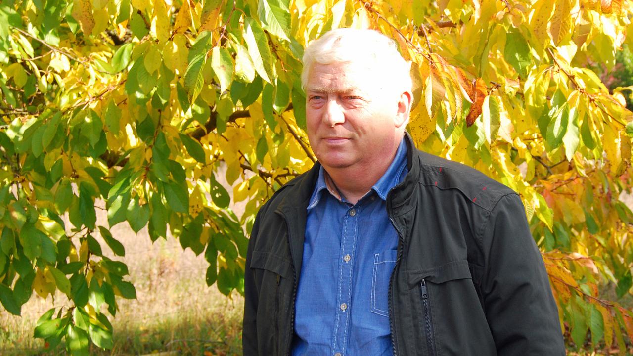 Peter Krenz vor einem Baum mit herbstlich gefärbten Blättern