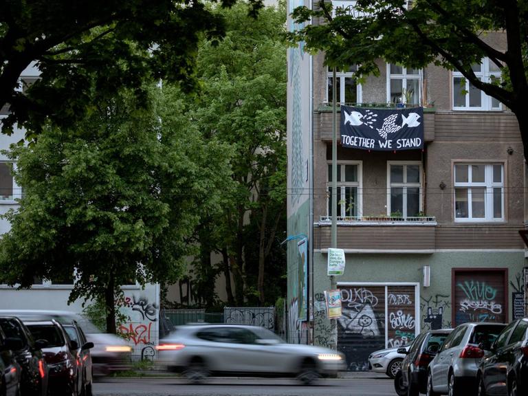 Vom Balkon eines Mietshauses in Berlin Friedrichshain hängt ein Plakat mit der Aufschrift "Together We Stand".