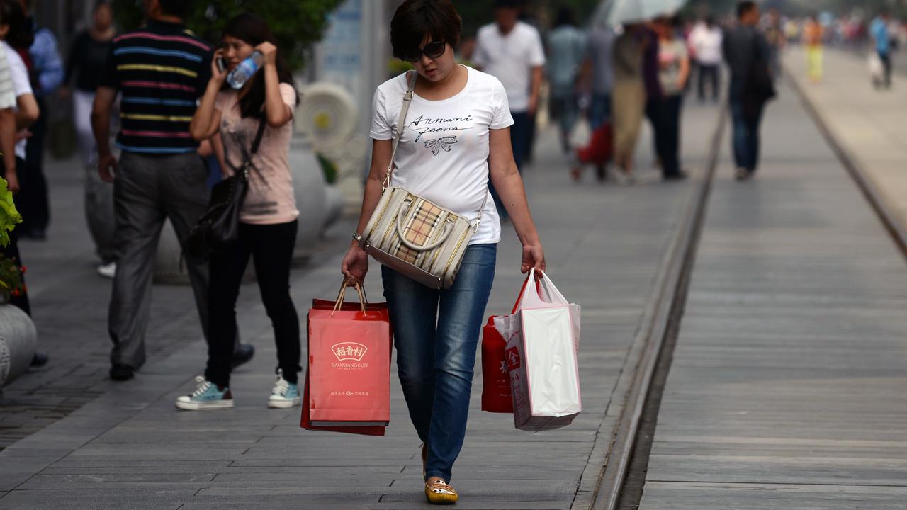 Eine Frau mit Einkaufstüten in einer Einkaufsstraße in Peking.