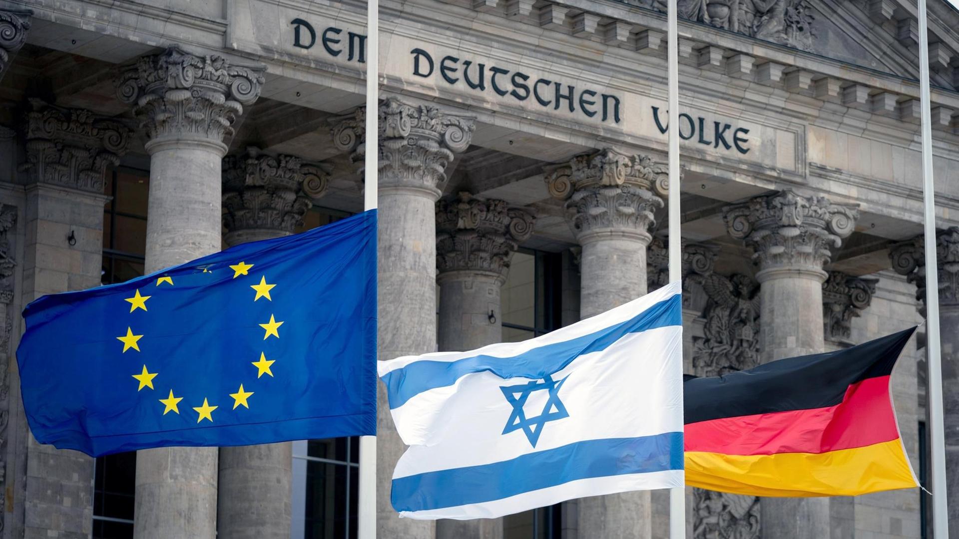 Die Fahnen von EU, Israel und Deutschland sind vor dem Bundestag halb hoch aufgezogen