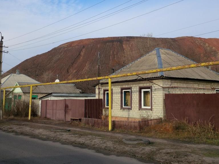 Mehrere Häuser stehen vor einem Berg an einer Straße. Mehrere Häuser stehen vor einem Berg an einer Straße.