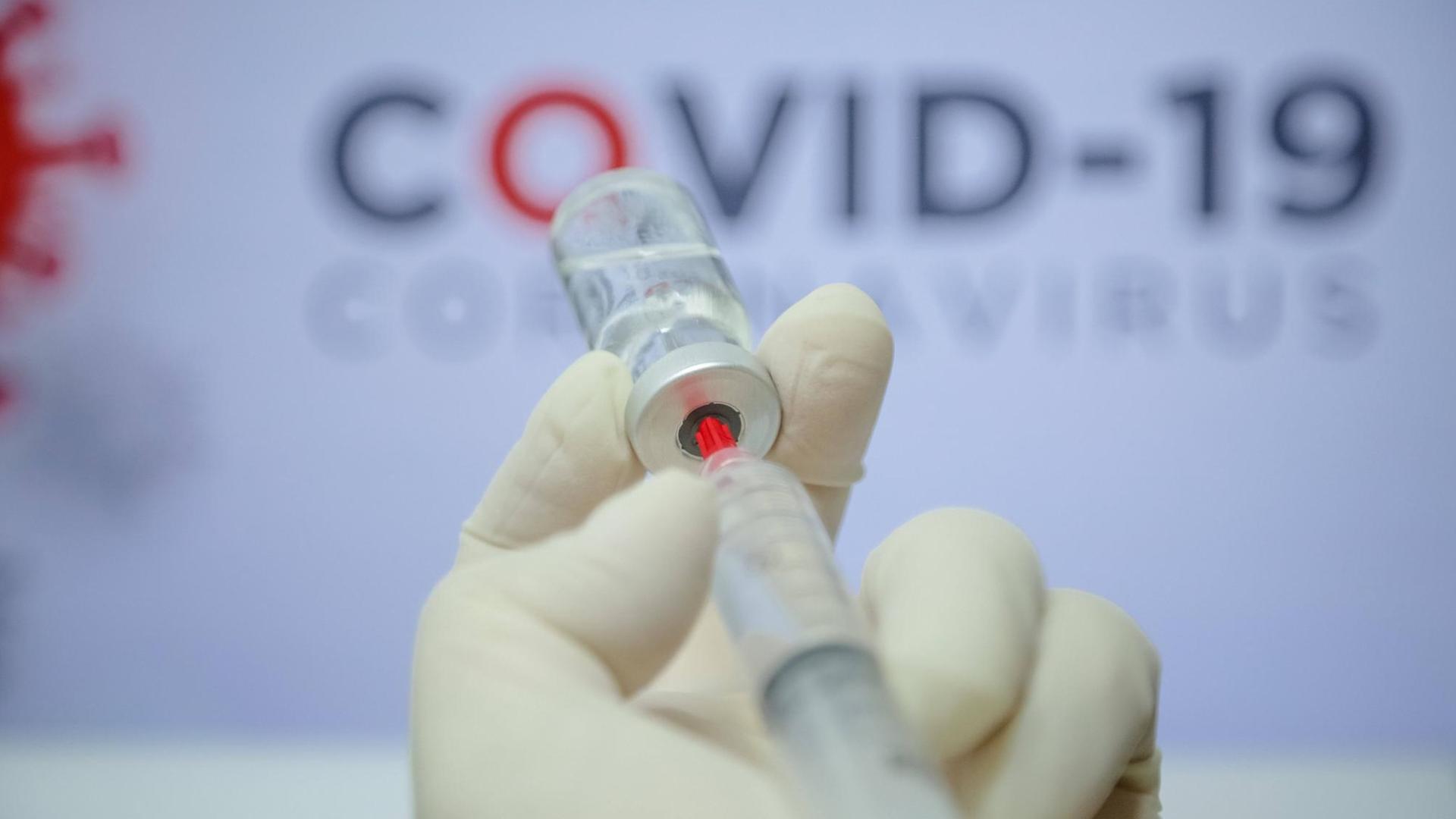 Ein Impfstoff wird mit einer Spritze einem Fläschchen entnommen (Symbolbild)