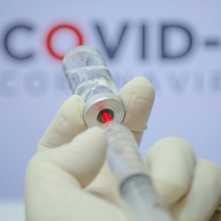 Ein Impfstoff wird mit einer Spritze einem Fläschchen entnommen (Symbolbild)