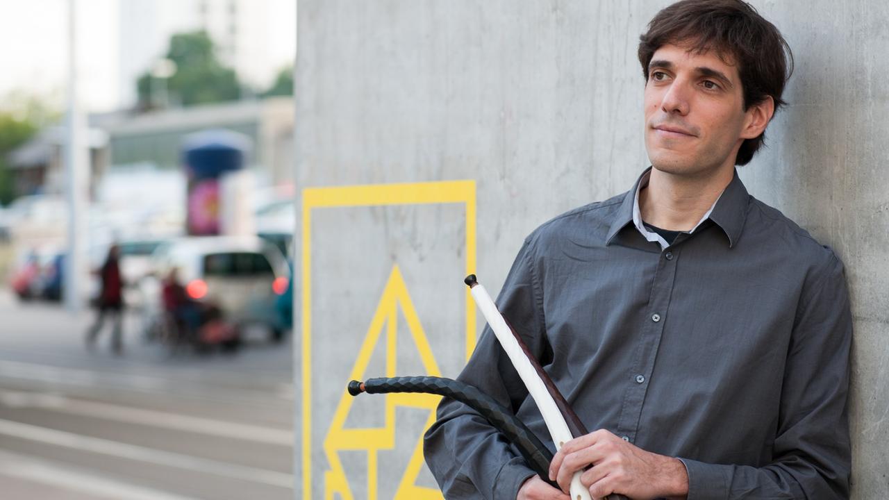 Ricardo Simian hält an eine Wand angelehnt Instrumente aus dem 3D-Drucker in der Hand