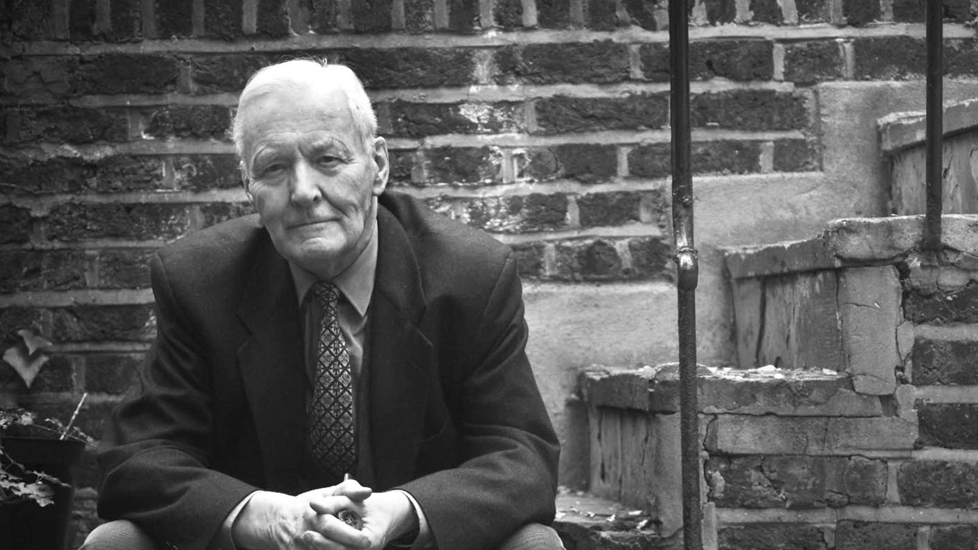 Tony Benn sitzt mit einer Pfeife in den Händen auf einer Treppe vor seinem Haus in London.