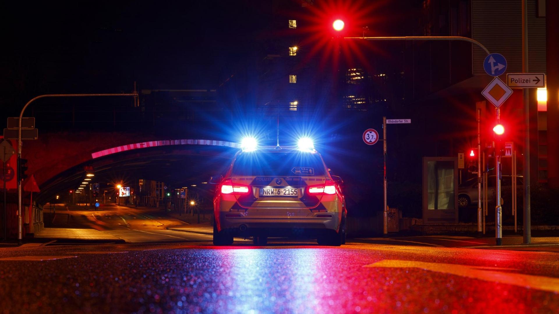 Ein Polizeiauto steht in der Nacht an einer roten Ampel.