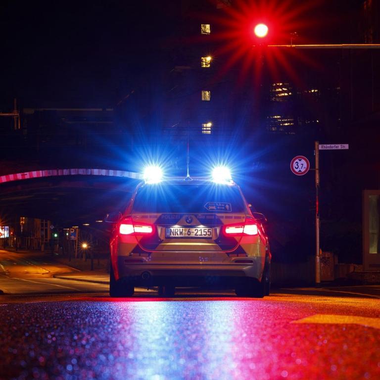 Ein Polizeiauto steht in der Nacht an einer roten Ampel. 

