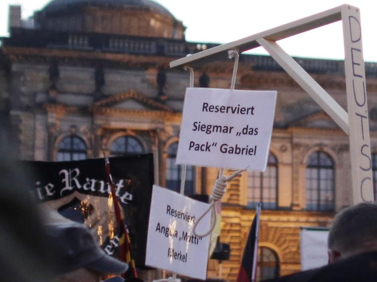 Auf einer Kundgebung der fremdenfeindlichen Pegida-Bewegung in Dresden am 12.10.2015 hält ein Demonstrant einen Galgen hoch, an dem zwei Schilder hängen. Darauf steht "Reserviert für Angela Merkel" und "Reserviert für Siegmar Gabriel".