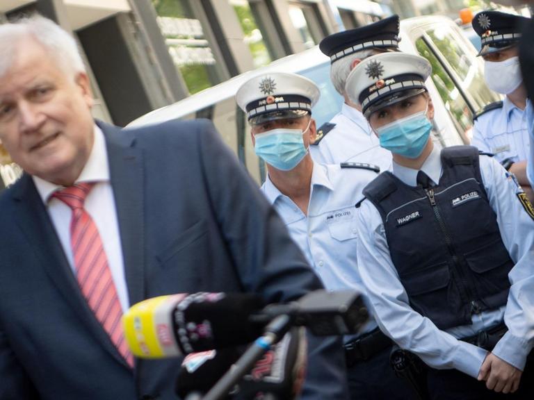 Bundesinnenminister Horst Seehofer steht in Stuttgart vor Polizisten, die einen Mundschutz tragen.