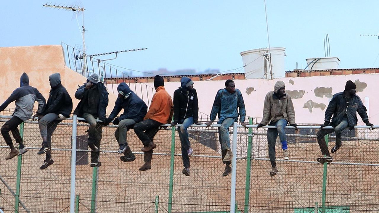 Migranten sitzen auf dem Grenzzaun zwischen Marokko und Spanien in Melilla.