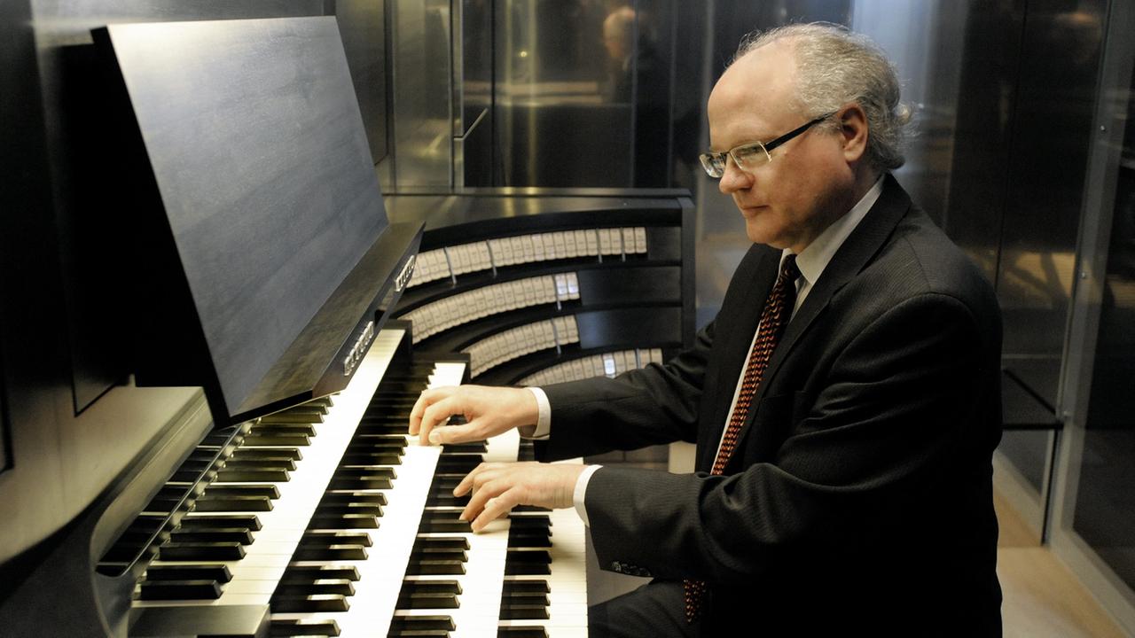 Ein Mann sitzt vor den Tasten eines Orgelspieltischs.